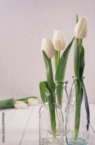 Three glass bottles with tulips in minimalistic.