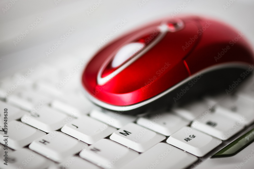 A beautiful red wireless mouse on the white keyboard of a laptop. Shallow depth of field A beautiful red wireless mouse on the white keyboard of a laptop. Shallow depth of field
