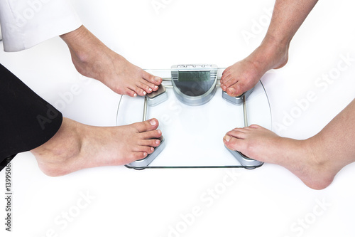 Lot female feet standing on bathroom scale over white background