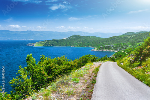 Wonderful romantic summer afternoon landscape panorama coastline Adriatic sea. A narrow mountain road above the cliffs along the coast. The clear azure water in the bay. Krk island. Croatia. Europe.