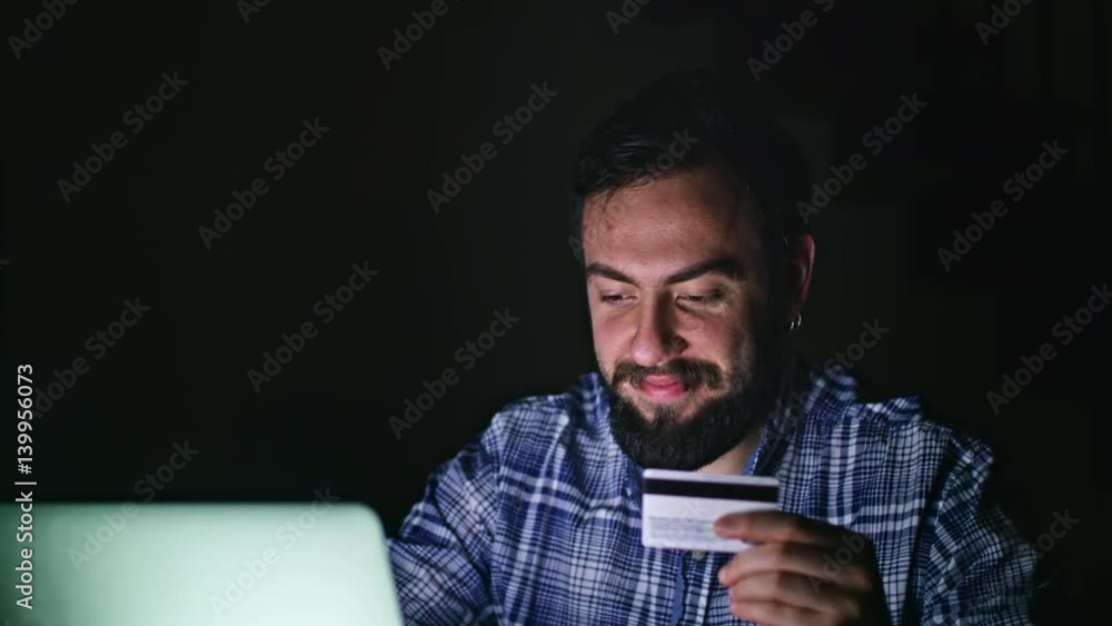 Close-up view of young man online shoping at home on pc, typing credit card number Close-up view of young man online shoping at home on pc, typing credit card number