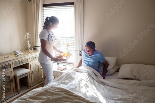 Doctor serving breakfast to senior patient