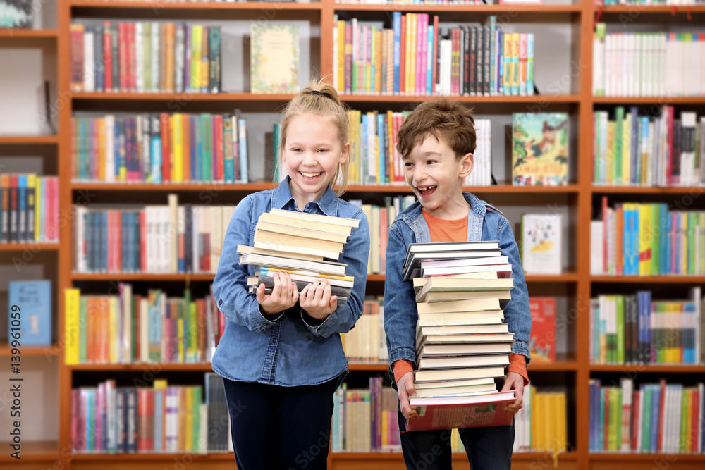 Cute boy and girl reading book in library