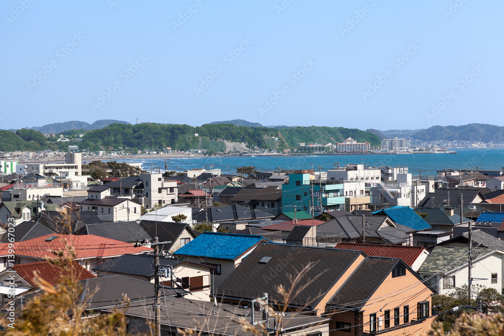 KAMAKURA, JAPAN - CIRCA APR, 2013: Top view at the Kamakura town. Houses with color roofs are on the coastline of Pasific ocean. Kamakura is a small town in Kanagawa Prefecture