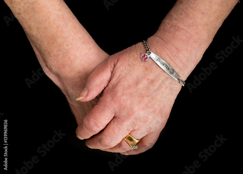 Elderly woman's hands with medical alert bracelet for diabetes.