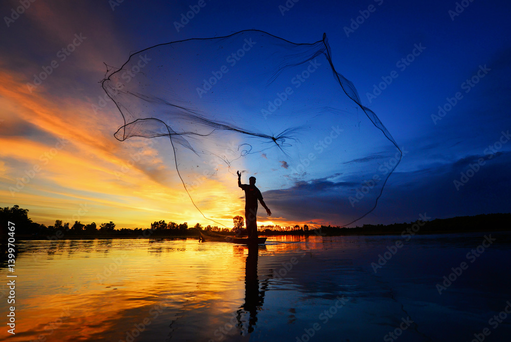 The silluate fisherman trowing the nets  on boat in river  at during sunset,Thailand fisherman,fisherman nets,fisherman sunset - obrazy, fototapety, plakaty 