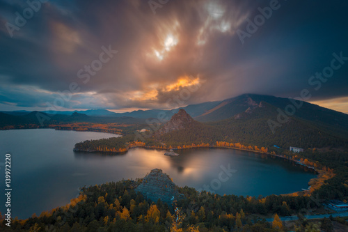 Dramatic autumn evening cloudscape at sunset. The bright colors of autumn around mountain lake. Kazakhstan. Asia.