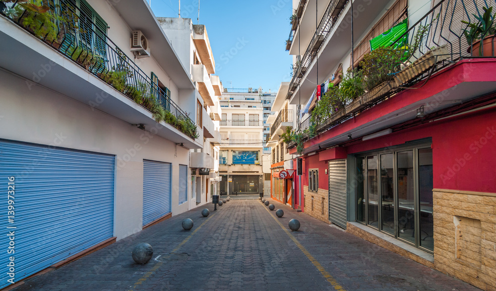 Vacant & shaded, empty alleyway on otherwise bright sunlit day in Sant Antoni De Portmany. Ibiza in quiet off-season in the afternoon. Vacant & shaded, empty alleyway on otherwise bright sunlit day in Sant Antoni De Portmany. Ibiza in quiet off-season in the afternoon.