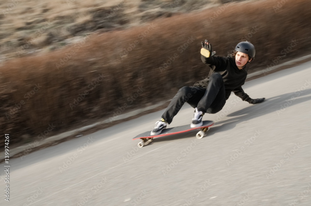 Young man in helmet is going to slide, slide with sparks on a longboard on the asphalt Young man in helmet is going to slide, slide with sparks on a longboard on the asphalt
