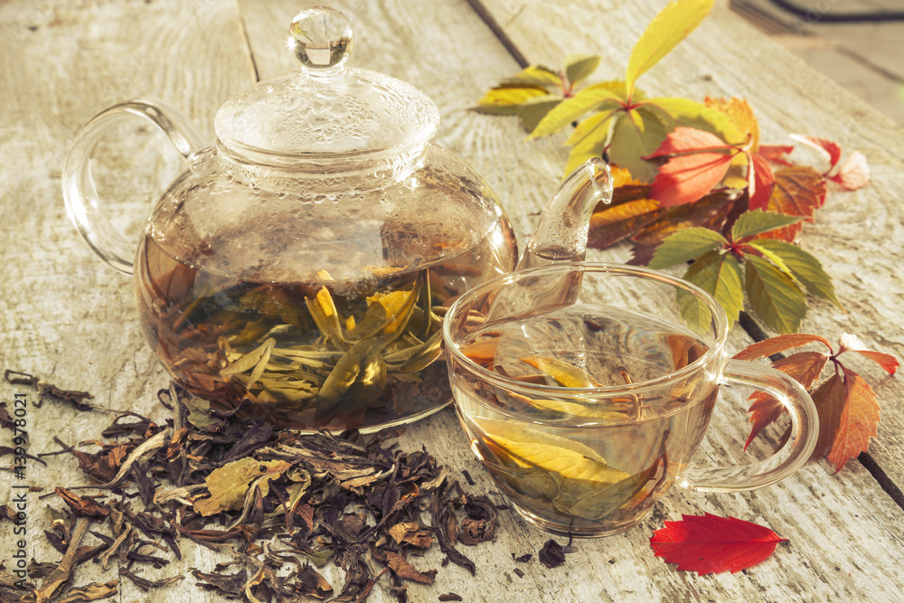 Fototapeta premium Glass teapot and cup with green tea on old wooden table. Glass teapot with tea.