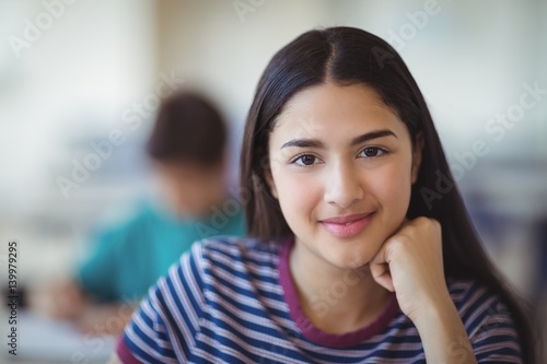 Portrait of happy schoolgirl sitting in classroom