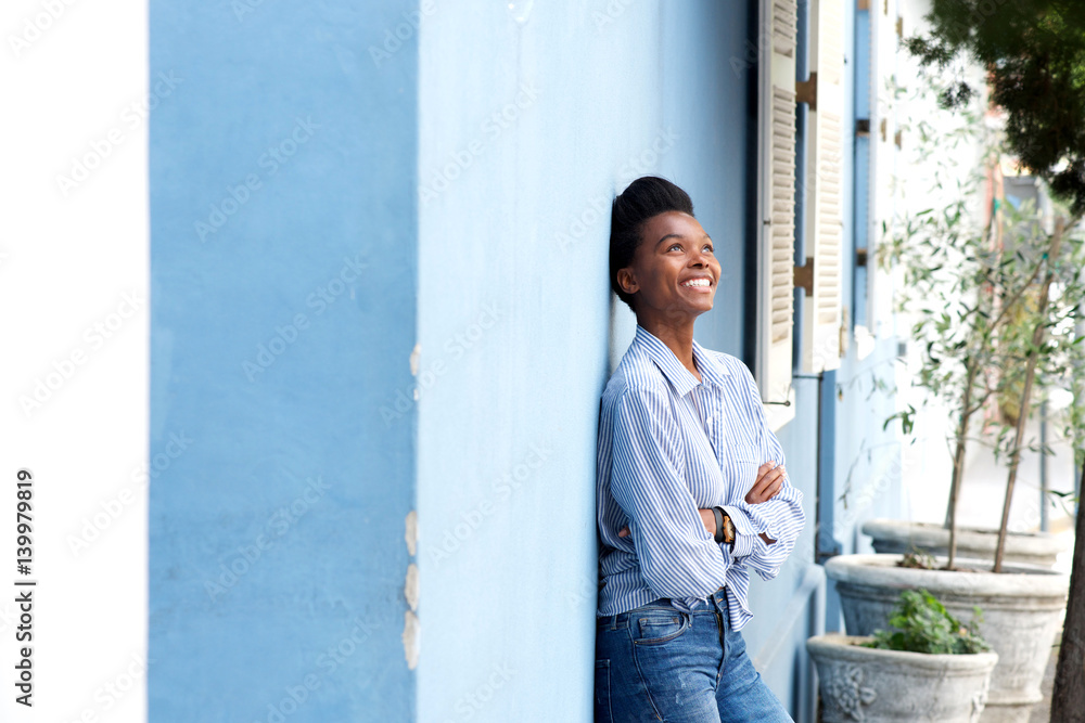 happy young black woman leaning against wall happy young black woman leaning against wall