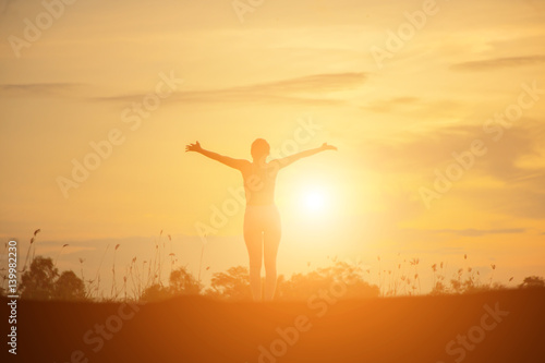 Silhouette of woman praying over beautiful sky background