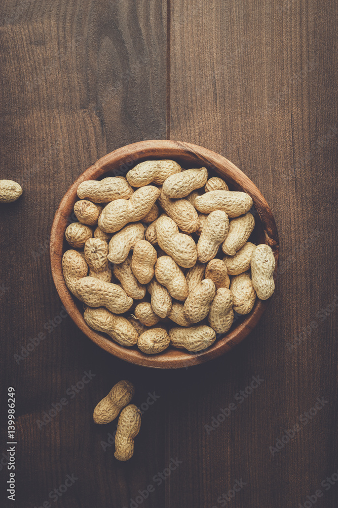 many roasted peanuts in wooden bowl on the table background many roasted peanuts in wooden bowl on the table background