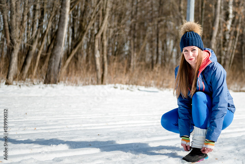 Beautiful young girl doing stretching, fitness on a sports field in winter against a background of deciduous forest. Winter sports concept photo © markhipov