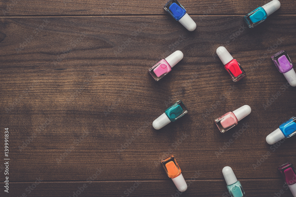 nail polish bottles of different colors on brown wooden table nail polish bottles of different colors on brown wooden table