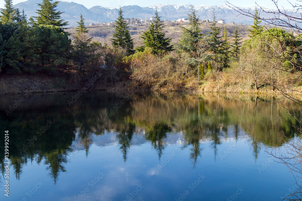 Reflection of trees on a smooth surface of a blue lake. Mountain landscape.