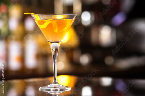 Fresh tall glass of tropical cocktail with rum and orange juice at bar counter background.