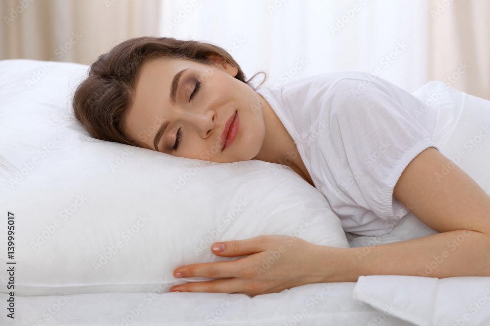 Beautiful young woman sleeping while lying in bed comfortably and blissfully. Early morning, you wake up for work or the day off concept Beautiful young woman sleeping while lying in bed comfortably and blissfully. Early morning, you wake up for work or the day off concept