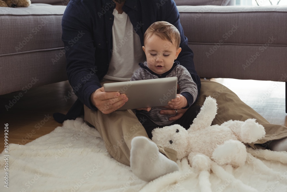 Father and baby using digital tablet in living room Father and baby using digital tablet in living room