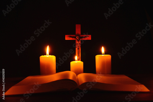 Crucifix and three burning candles with open bible on table in the darkness. Pray to Jesus Christ. Hope on good life. 4