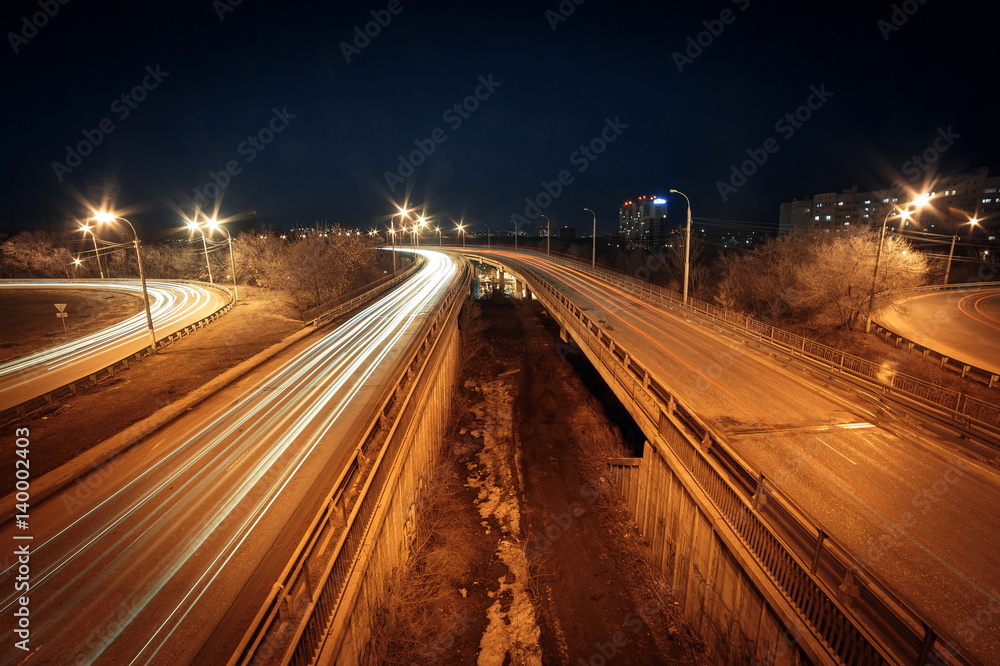 Light trails at night on the road with overpass