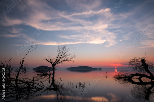 Sunset on the lake with trees  reflections and clouds