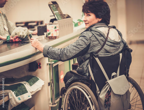 Disabled woman in a wheelchair paying with credit card in a store photo