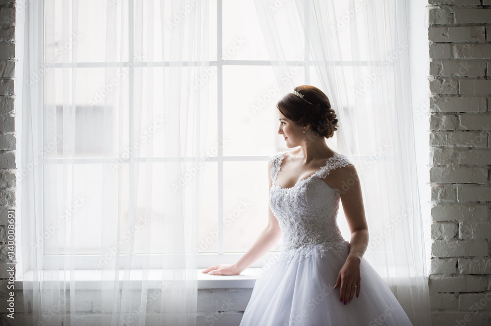 Beautiful bride with bouquet before wedding ceremony near window Beautiful bride with bouquet before wedding ceremony near window
