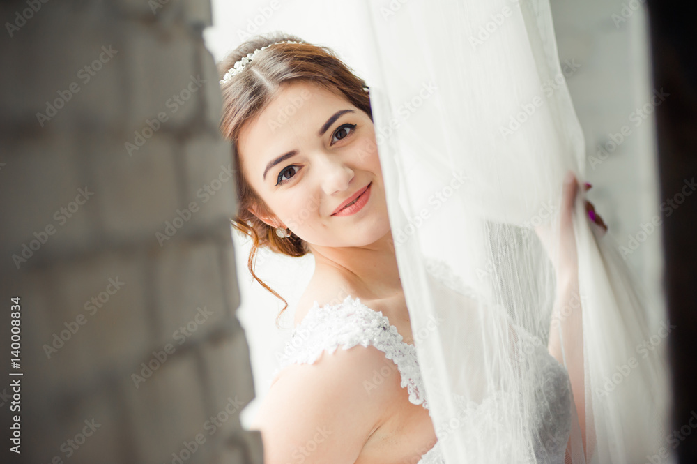 Beautiful bride with bouquet before wedding ceremony near window Beautiful bride with bouquet before wedding ceremony near window