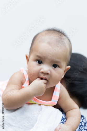 Beautiful baby portrait with hand in mouth on white background