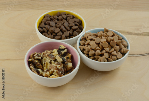 Chocolate chips, peanut butter chips and walnut toppings in bowls