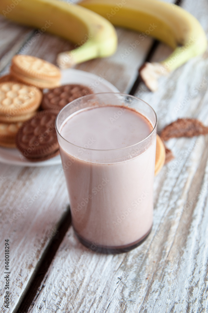 Photo of fresh Made Chocolate Banana Smoothie on a wooden table with cookies. Photo of fresh Made Chocolate Banana Smoothie on a wooden table with cookies.
