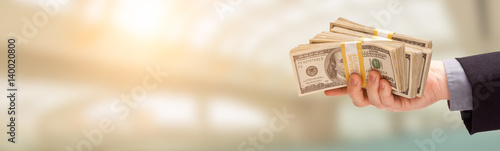 Male Hand Holding Stack of Cash Wide Banner With Room For Copy.