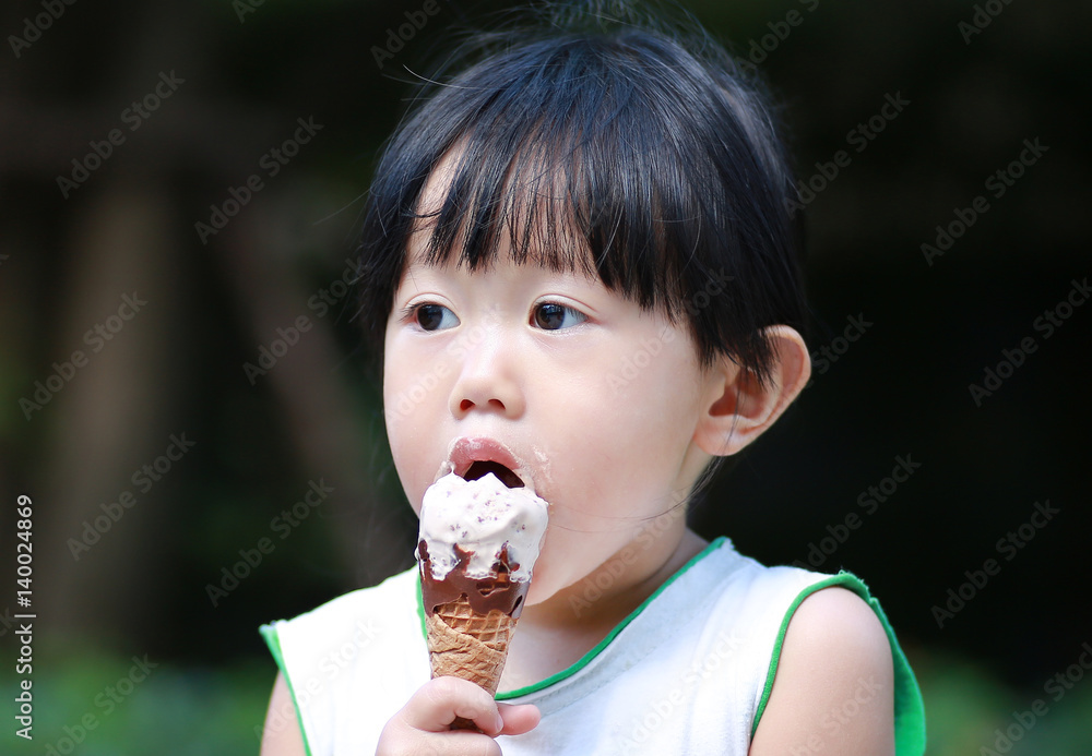 Kid girl eating ice cream in the garden Kid girl eating ice cream in the garden