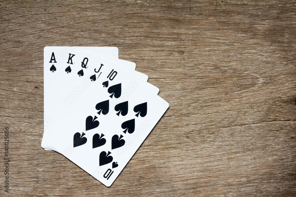 Five card of black spade royal straight flush on wooden background