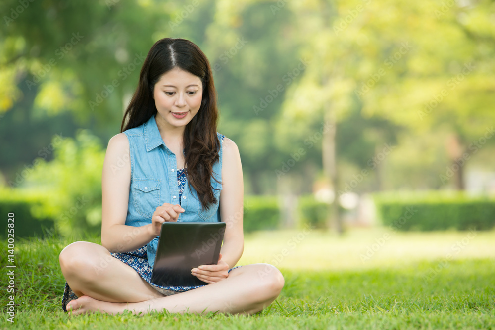 beauty asian woman using digital tablet sitting on grass beauty asian woman using digital tablet sitting on grass
