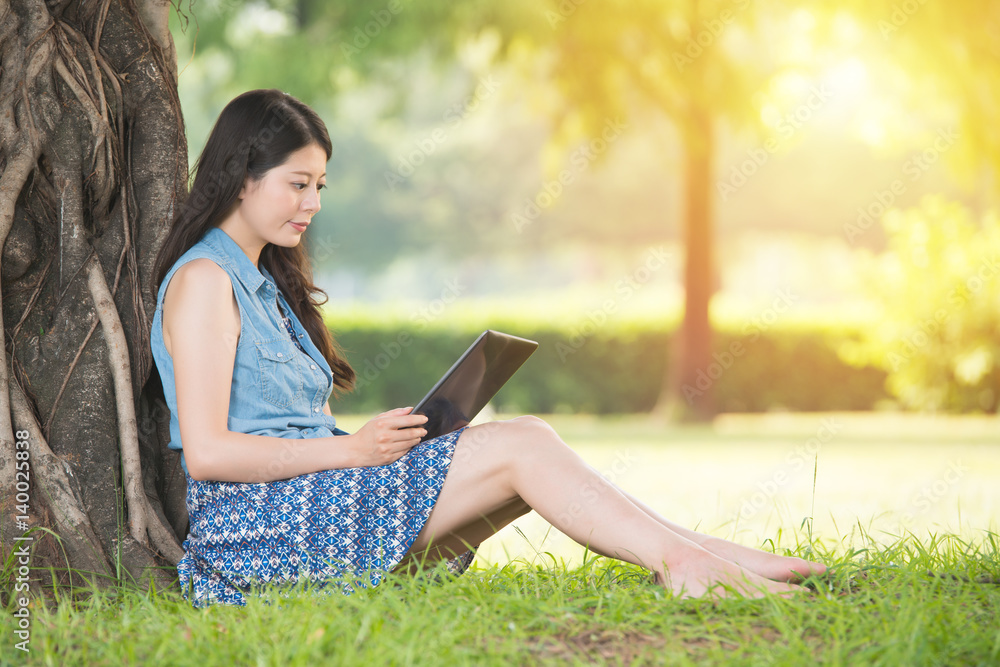 Fototapeta premium beauty asian woman using digital tablet sitting on grass