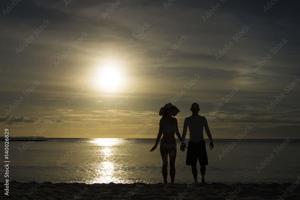 夕暮れのビーチと男女のシルエット
