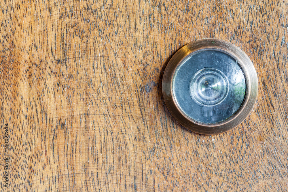 Detail of old lens peephole on wooden door background.