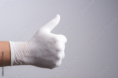 Hand wearing latex glove with thumb up gesture
