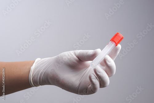 Hand with latex glove holding empty test tube