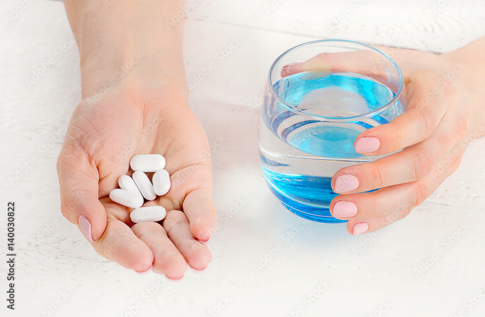 Young woman holding a glass of water and pills. Healthcare and medical concept. Top view Young woman holding a glass of water and pills. Healthcare and medical concept. Top view