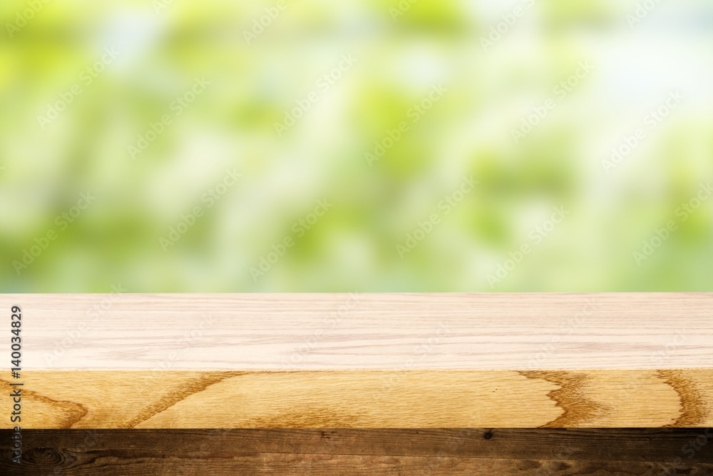 Top wooden table and in the background blurred plants as a theme spa. Empty space to paste and mounting of different products. Top wooden table and in the background blurred plants as a theme spa. Empty space to paste and mounting of different products.