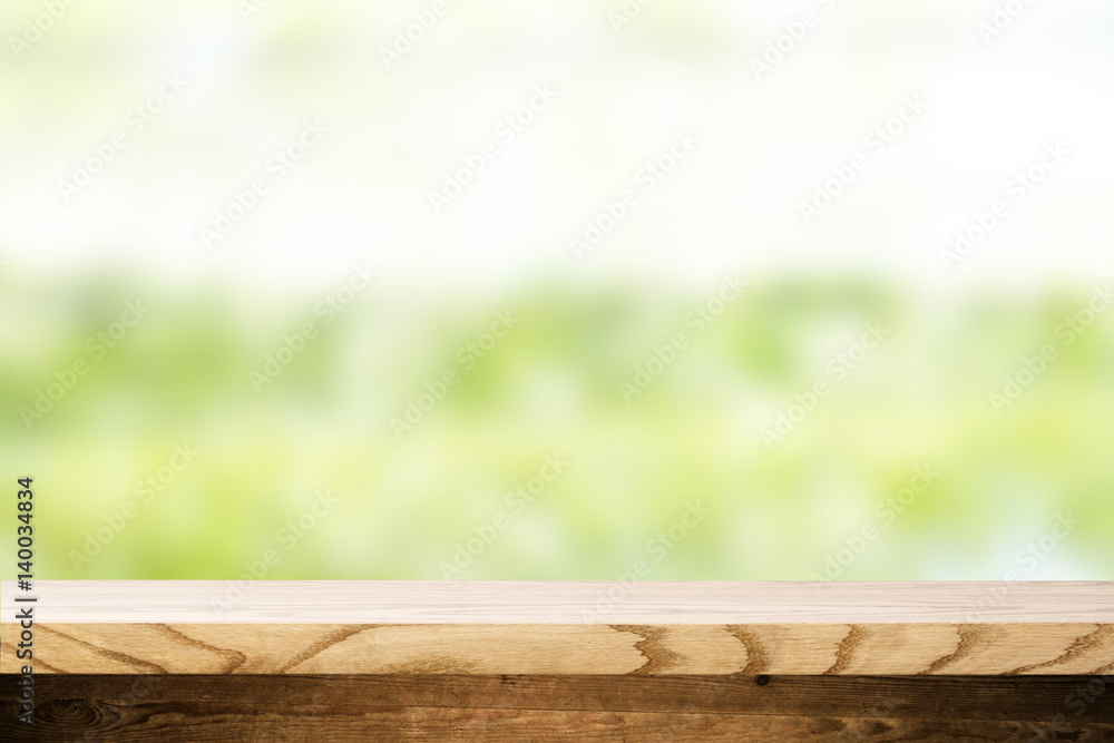 Top wooden table and in the background blurred plants as a theme spa. Empty space to paste and mounting of different products. Top wooden table and in the background blurred plants as a theme spa. Empty space to paste and mounting of different products.
