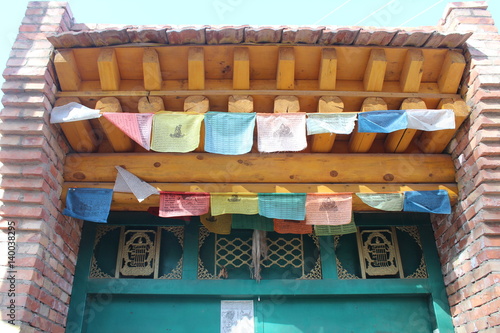 Amdo Tibetan Village Wooden Home Gate with Prayer Flags © Kim