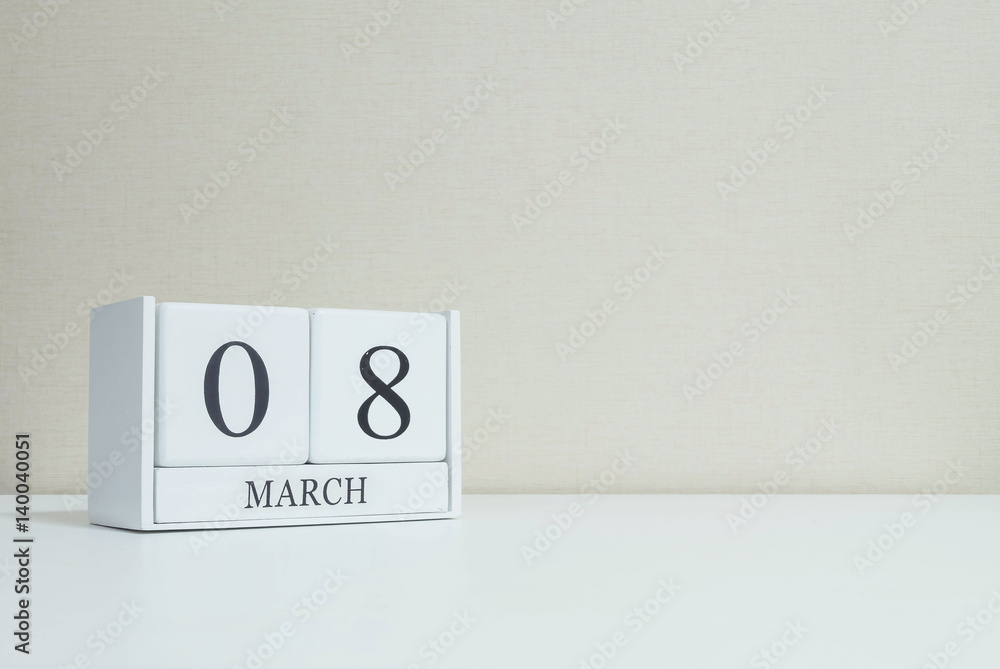 Closeup white wooden calendar with black 8 march word on blurred white wood desk and cream color wallpaper in room textured background with copy space , selective focus at the calendar Closeup white wooden calendar with black 8 march word on blurred white wood desk and cream color wallpaper in room textured background with copy space , selective focus at the calendar