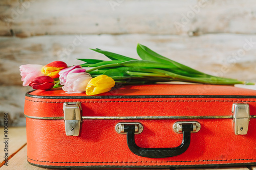 tulips in red suitcase. woden background
