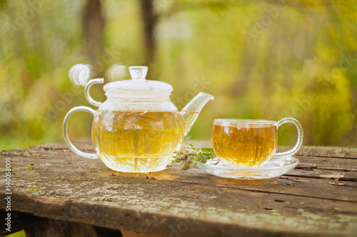 Green tea in beautiful teapot on wooden table outdoors