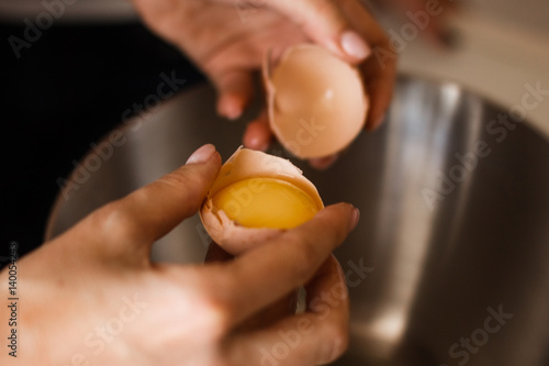 Hand break an egg and pouring into bowl. Key ingredient for tasty omelet and separates albumen from yolk. Ingredient for high-protein dish..